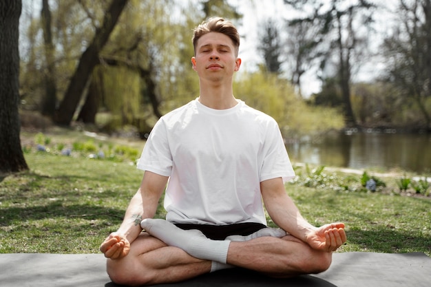 Full shot man meditating outdoors